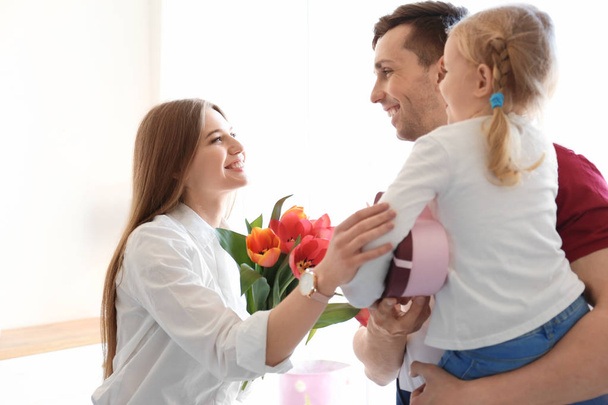 Happy woman receiving flowers and gift from her family at home. Mother's day celebration - Foto, Bild