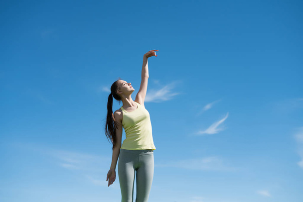 a harmonious, tranquil girl engaged in yoga under the blue sky, meditates and relaxes - 写真・画像