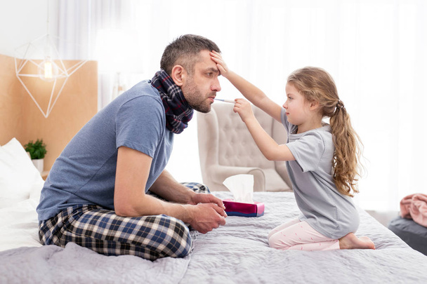 Concentrated girl treating her sick father  - Foto, Imagem