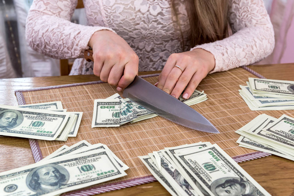 Frauenhände schneiden Dollar-Banknoten auf Holztisch - Foto, Bild