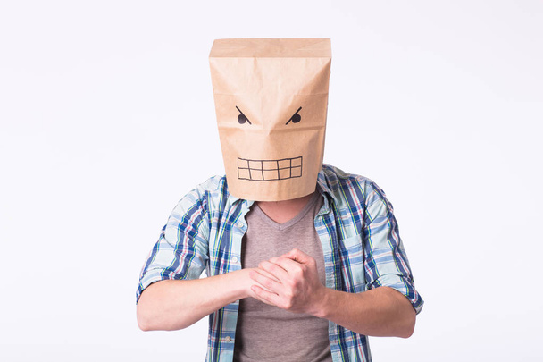 Homem com caixa de papelão na cabeça e desenho de rosto emoticon irritado. Zangado homem começando uma luta
. - Foto, Imagem