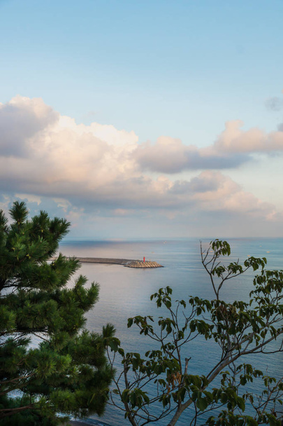Leuchtturm und Wolkenlandschaft im Ozean mit Wellenbrechern bei Sonnenuntergang an der Yongmeori-Küste, Sanbang-ro, Insel Jeju, Südkorea - Foto, Bild