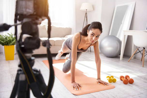 Charming woman filming vlog and doing a plank - Fotoğraf, Görsel