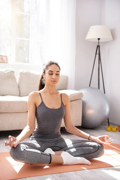 Charming young woman practicing yoga at home - 写真・画像
