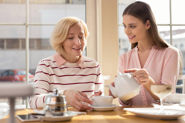 Alert granddaughter having tea with her granny - Zdjęcie, obraz