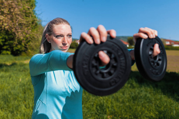 Young woman lifts weights in a sport dress - Photo, Image