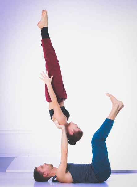 Young athletic couple practicing acroyoga. Balancing in pair. - Фото, зображення