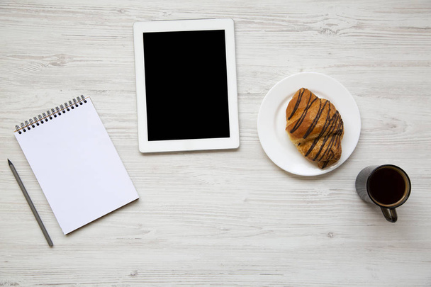Werkruimte met Tablet PC- en laptop op witte houten achtergrond. Koffie en croissant. Bovenaanzicht. Plat leggen. - Foto, afbeelding