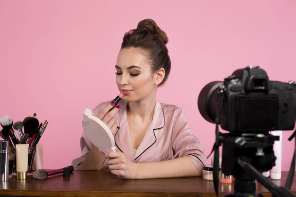 Positive female blogger is filming makeup tutorial - Foto, afbeelding