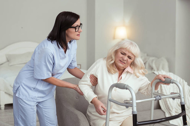 Attentive nurse aiding elder woman - 写真・画像