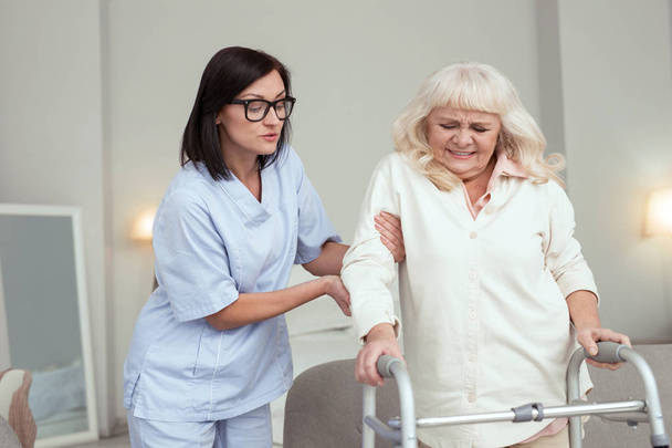 Experienced nurse comforting elder woman - Foto, imagen