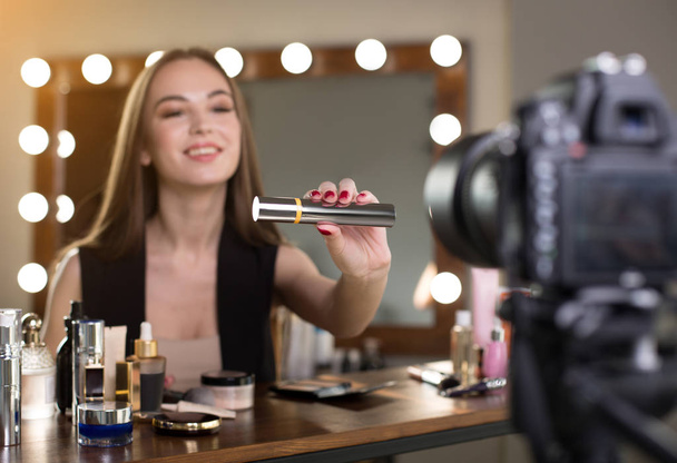 Positive young vlogger is showing new cosmetics product - Foto, Bild