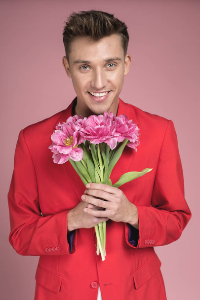 Cheerful guy keeping flowers in arms - Photo, Image
