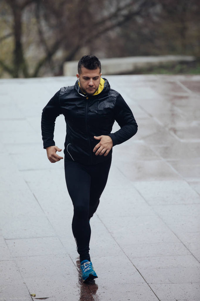 Sports man jogging outdoors in rainy day - Foto, afbeelding