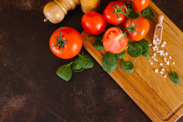 Tomates frescos, albahaca, sal marina con cuchara sobre tabla de madera
 - Foto, imagen
