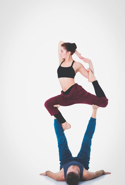 Young athletic couple practicing acroyoga. Balancing in pair. - Foto, afbeelding