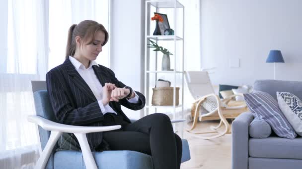 Nő segítségével Smartwatch kanapén ülve - Felvétel, videó