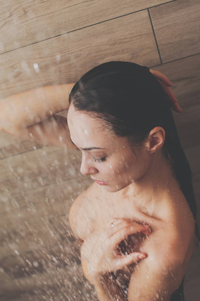 Young beautyful woman under shower in bathroom. - Foto, immagini