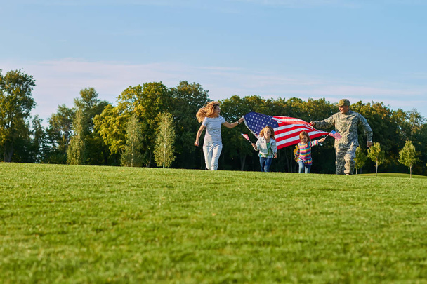 Patriotic family with huge usa flags outdoors. - Photo, Image