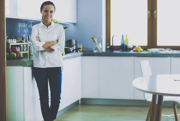Portrait of young woman standing with arms crossed against kitchen background. Woman in the kitchen. - Foto, Imagen