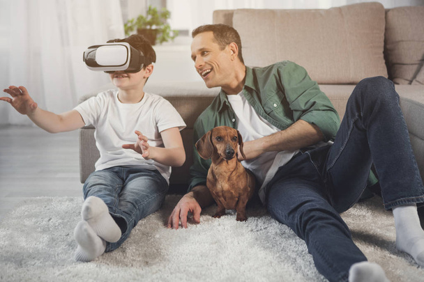 Happy son and dad entertaining with modern device at home - Фото, зображення