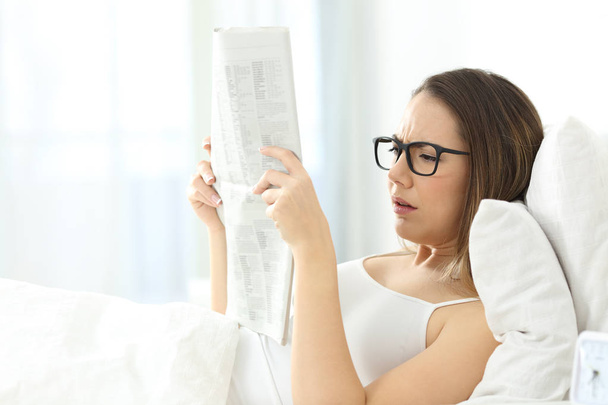 Girl wearing eyeglasses having problems to read a newspaper - Foto, Imagem
