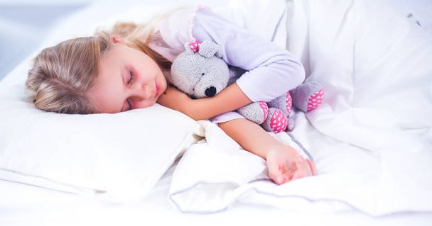 Child little girl sleeps in the bed with a toy teddy bear - Foto, Imagen