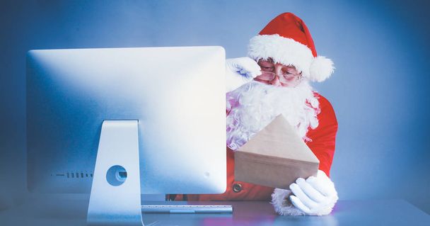 Santa Claus reading children letters and writing responses to them using laptop . - 写真・画像