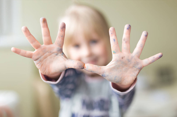 Happy little kid showing hands dirty with paint. Enjoying art and painting concept - Photo, Image