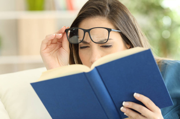 Woman suffering eyestrain reading a book - Foto, immagini