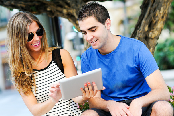 Attractive couple with tablet computer in urban background - Photo, Image