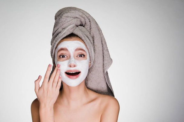 beautiful young girl with a towel on her head, after showering, applied a useful moisturizing face mask - Foto, immagini