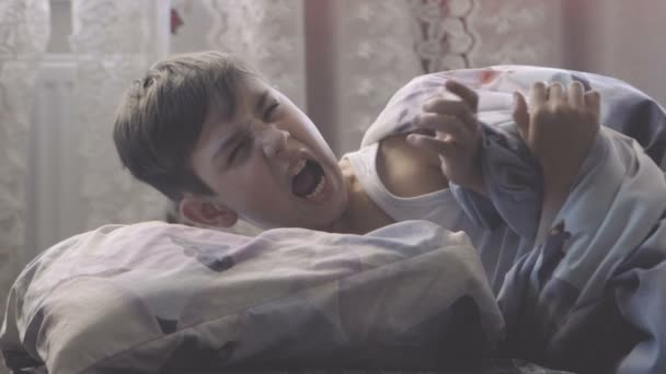 boy woke up in the morning in his bed and picked up a smartphone - Materiał filmowy, wideo