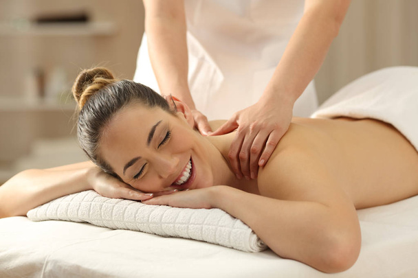 Happy woman receiving a massage in a spa - Foto, afbeelding