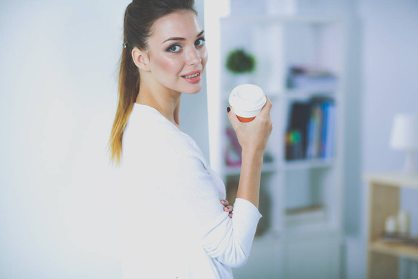Attractive businesswoman standing near wall in office with book. - Zdjęcie, obraz