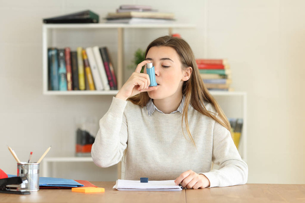 Student using an asthma inhaler at home - Foto, imagen