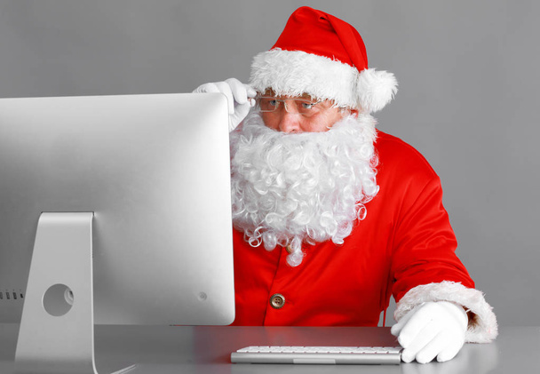 Santa Claus reading children letters and writing responses to them using laptop . - Фото, изображение
