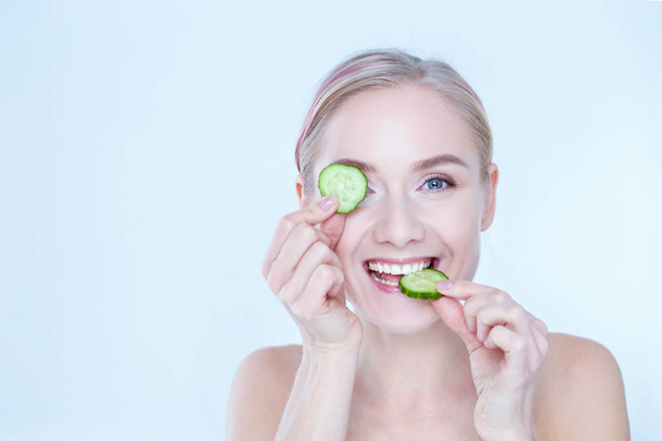 Young beautiful woman with cucumber slices on white background - Photo, Image
