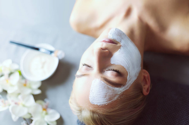 Face mask.Beautiful young girl at spa ,cosmetician woman applying facial mask - Photo, Image