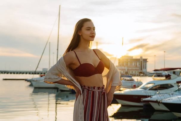 long-haired stylish young girl stands in seaport, relaxes and smiles - Foto, immagini