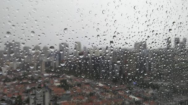 Regentropfen auf Fenster mit verschwommenem Hintergrund der Stadt  - Foto, Bild