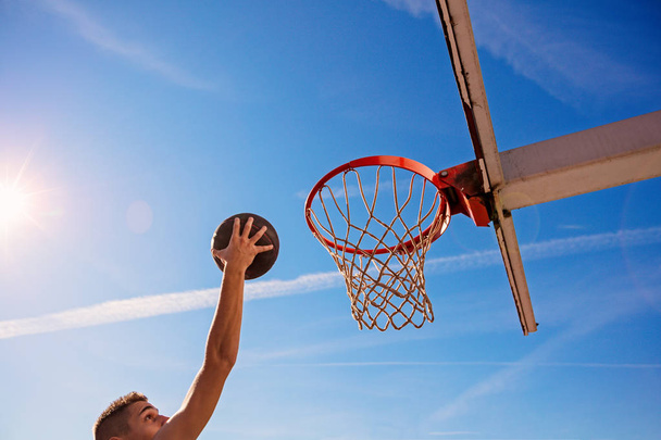 Slam Dunk. Side view of young basketball player making slam dunk - Фото, изображение