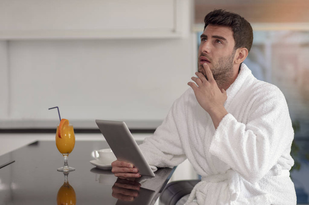 young freelancer in bathrobe working from home using tablet computer - Foto, Imagen