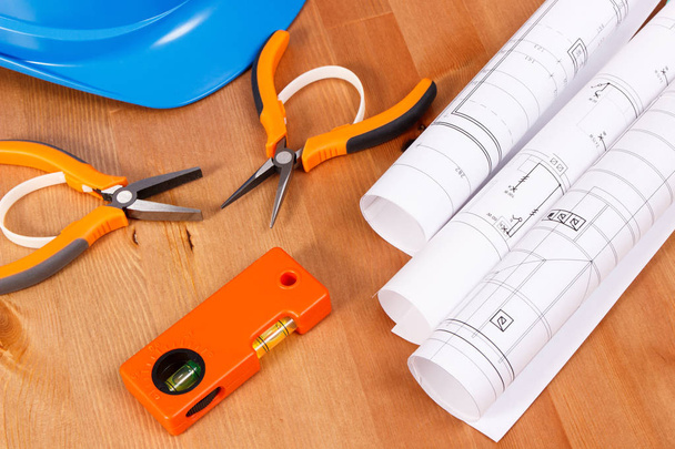 Dibujos eléctricos, casco azul protector y herramientas de trabajo naranjas para trabajos de ingeniería en el escritorio
 - Foto, imagen