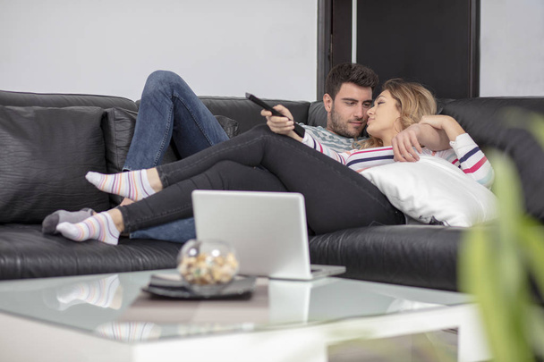 Happy young couple relaxing and watching TV at home. - Valokuva, kuva