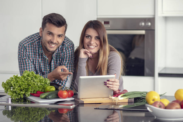 Portrait of happy young couple cooking together in the kitchen at home. - Photo, Image
