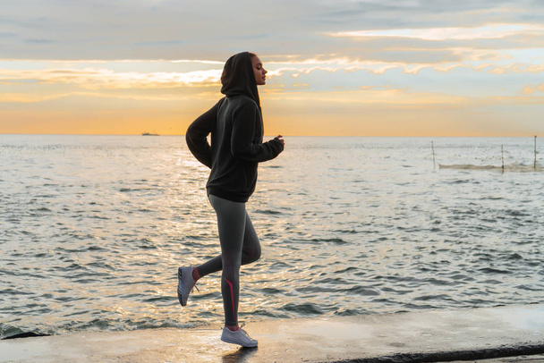 slender athletic girl runs around the sea at sunset, wants to lose weight - Photo, Image