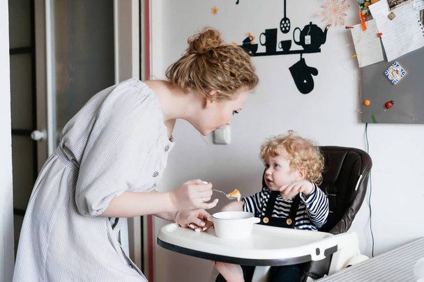 petit déjeuner familial, une jeune mère nourrit son jeune fils, dans la cuisine, une céréale utile
 - Photo, image