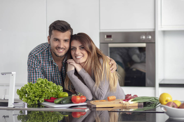 Portrait of happy young couple cooking together in the kitchen at home. - 写真・画像