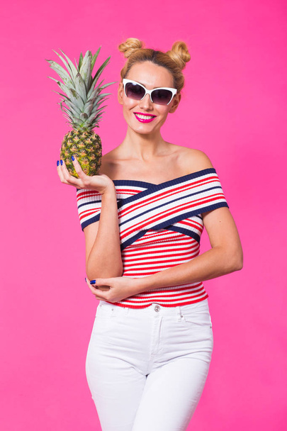 Fashion portrait woman with sunglasses and pineapple over pink background - 写真・画像